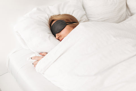 woman wearing eye mask and a weighted blanket to sleep